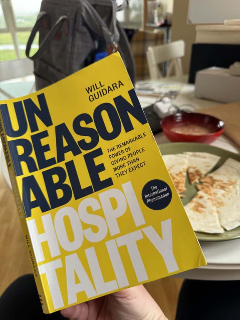Unreasonable Hospitality by Will Guidara held up at the lunch table, part of a daily reading habit over quesadillas